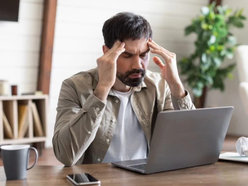 Photo d'un professionnel se tenant la tête à cause de problème de gestion d'entreprise.